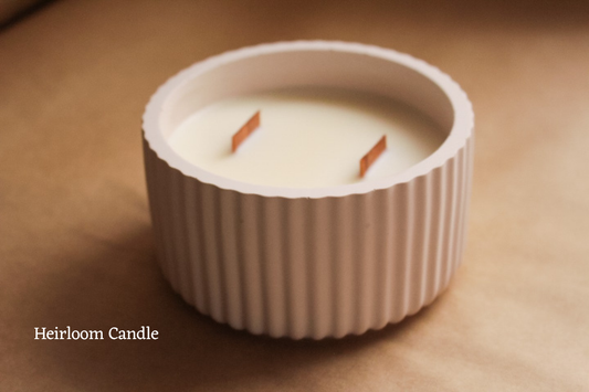Candle in a ribbed container on a brown background with 'Heirloom Candle' text.
